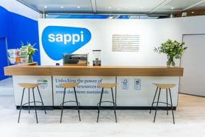 Der Empfangsbereich am Messestand von Sappi mit dem Schriftzug „Die Kraft erneuerbarer Ressourcen nutzen, um jeden Tag nachhaltiger zu werden“.
