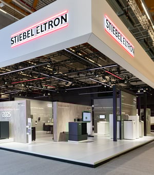 Messestand von STIEBEL ELTRON auf der ISH 2025 mit modernem Design, grauen und roten Akzenten sowie Präsentationsflächen für Heiz- und Energielösungen.