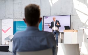 Person hört einem Redner in einem Vortragssaal zu.