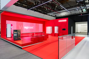 Präsentationszone des STIEBEL ELTRON Messestandes mit auffälliger roten Plattform und Exponaten für Wärmepumpen und Energietechnik.