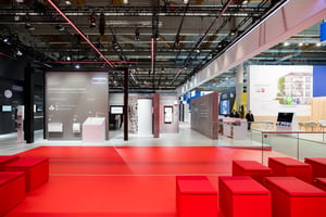 Offener Bereich des STIEBEL ELTRON Messestandes mit roten Sitzwürfeln und Informationswänden zu innovativen Wärmelösungen.