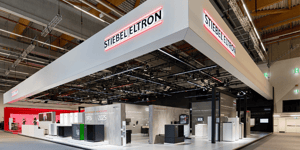 Messestand von STIEBEL ELTRON auf der ISH 2025 mit modernem Design, grauen und roten Akzenten sowie Präsentationsflächen für Heiz- und Energielösungen.