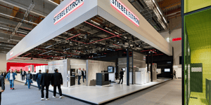 Offener Bereich des STIEBEL ELTRON Messestandes mit roten Sitzwürfeln und Informationswänden zu innovativen Wärmelösungen.