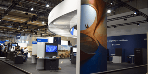 Overall view of the Trimble booth with curved white elements, modern screens, and open meeting areas.