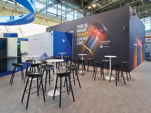 Meeting area on the Trimble exhibition stand with high tables, seating and a large-scale product graphic on the rear wall.