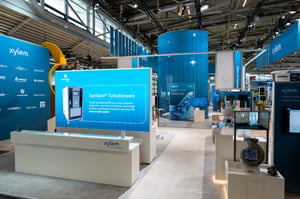 Reception area of the Xylem exhibition stand with a large LED display showing informative text and products.