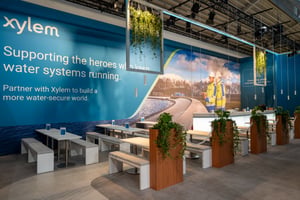 Detail shot of Xylem's exhibition booth with a big seating area, printed walls and plants.