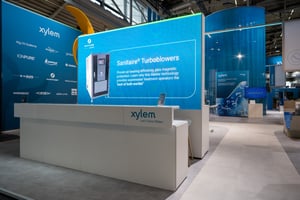 Reception area of Xylem's exhibition booth with a big LED screen showing informational text and products.