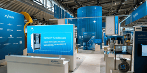 Reception area of the Xylem exhibition stand with a large LED display showing informative text and products.