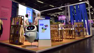 Section of the Haufe Group booth with info terminals, books, and a robot element as an eye-catching feature.