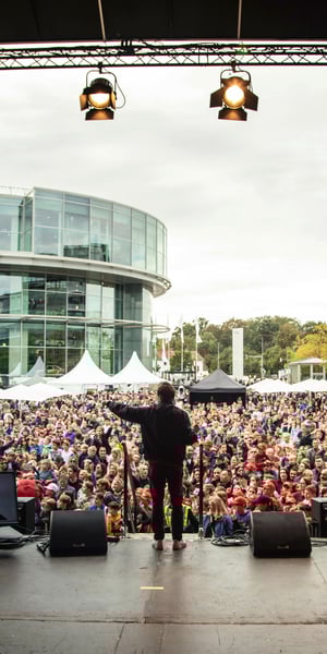 Performer on a stage standing in front of a big crowd during the Audi Family event.
