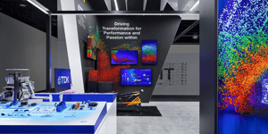 Close-up of the TDK booth at CES 2025 with a black backdrop and vibrant graphics. High-tech components displayed on white tables.
