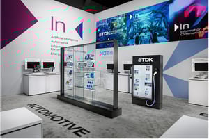 Messestand von TDK auf der CES 2026 mit Glasvitrine, LED‑Screens und grafischen Wänden zu Automotive und Artificial Intelligence.