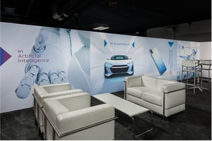 TDK Meeting‑Lounge auf der CES 2026 mit weißem Mobiliar und Wandgrafiken zu Artificial Intelligence und Automotive.
