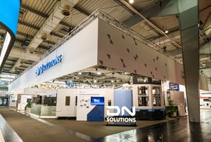 Full screen shot of the DN Solution exhibition booth with white banners and logo displays.