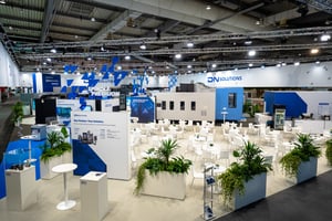 Hospitality area of the booth with plants, seating arrangement and informative displays.