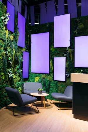 Close-up of the Haufe Group booth with a green plant wall and decorative purple panels creating a modern atmosphere.